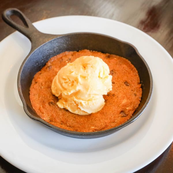 Warm chocolate chip cookie skillet topped with a scoop of vanilla ice cream from Red Rooster.